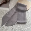 Makro-Detail von grauem Plissee-Seidenschal mit asymmetrischen Enden auf Holztablett - 130*9cm / Grau