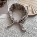 Flat-lay detail of a classic plaid cotton scarf with fine stitching on a soft background - Off White