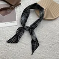 Dettaglio di un foulard di seta a quadri bianchi e neri annodato a fiocco su fondo bianco - Nero
