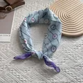 Detailansicht eines vintage hellblauen Seidentuchs mit handgerollten Kanten und Blumen - Schleife