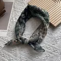 Detailed macro view of the vintage paisley print and fine texture of the square cotton scarf - Green