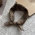 Détail d'un foulard en soie marron à motif cachemire noué en nœud sur fond texturé - 58*58cm / Café