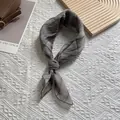 Detail showing grey pleated skinny scarf with vertical texture tied in a bow - 70x70 / Gray