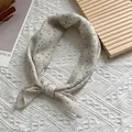 Detail van een crème zijden sjaal met grijze stippen en bloemenprint in een knoop - 58x58cm / Abrikoos