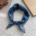 Detail eines dunkelblauen Seidenschals mit Blumenmuster, gebunden an einer Handtasche - 58x58cm / Blau