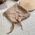 Detailed texture of khaki linen tie-dye triangle scarf with waffle pleats on a table - Khaki