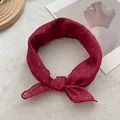 Close-up of a burgundy polka dot silk scarf with elegant bow design and soft texture - Red