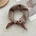 Dettaglio di un foulard di seta marrone con motivo pied de poule annodato ad anello - caffè