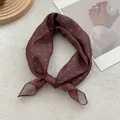 Close-up of knotted brown polka dot scarf on a textured background with elegant decor - Coffee