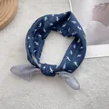Detailed view of navy blue silk scarf featuring a white horse pattern knotted as an accessory - 58*58cm / Navy Blue