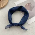 Close-up of retro white polka dot silk scarf tied in a bow on a textured background - Navy Blue