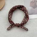 Detailed view of dark brown paisley silk scarf tied in a knot on white fabric background - Coffee