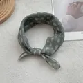 Close-up of retro dark green paisley print scarf tied in a knot on knit background - Green