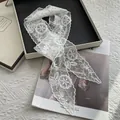 Detailed view of intricate white floral embroidery lace scarf on elegant magazine background - White