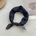 Detailed view of dark blue paisley silk scarf styled as a headband on white texture - 58x58cm / Black