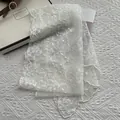 Elegante bufanda de encaje blanco roto con bordado floral y perlas sobre revista - Estilo Bordado de Encaje con Perlas / Blanco Roto