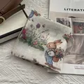 Gros plan d'un foulard en coton et lin avec motif de lapin à côté d'un sac et d'un magazine - Petit Lapin