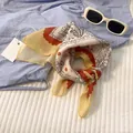 Detailed view of white paisley cotton scarf with red wavy borders on blue fabric background - 58x58cm / White Red Paisley
