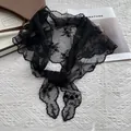 Dettaglio del foulard in pizzo nero con ricami floreali su sfondo di tessuto bianco - Nero