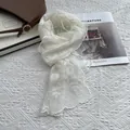 White sunflower lace scarf with floral embroidery and scalloped edges on white surface - Off White