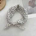 Detail of a white polka dot cotton linen scarf tied in a bow on a wooden tray - Off White