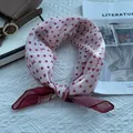 Close-up of pink polka dot silk scarf with bow pattern on a soft textured surface - 58x58cm / Red