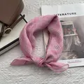 Dettaglio di un foulard in cotone a quadretti rosa annodato su sfondo bianco materico - 58x58cm / Rosa