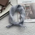 Dettaglio di un foulard in cotone a quadri blu annodato a una borsa in pelle vintage - 58x58cm / Grigio