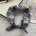Detail of soft black and white plaid scarf on an elegant white textured surface - Black