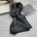 Detalle de una bufanda gris oscuro de algodón y lino arrugado con una elegante caja de regalo - gris oscuro