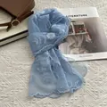 Detail of light blue lace scarf with white floral embroidery and wavy lace edges - Blue