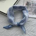 Detail of blue and white checkered scarf with polka dots on a textured fabric - Blue