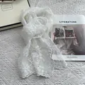 Close-up of white lace scarf with floral embroidery and pearl details on a desk - White