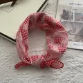 Detail of red and white checkered square scarf with heart patterns in a gift box - Red