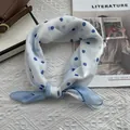 Morbido foulard di seta bianca a pois blu annodato su uno sfondo lifestyle elegante - 58*58cm / Blu