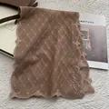 Detail of floral lace embroidery with wave edges and personalized script on brown fabric - Khaki