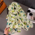 Detail of light green cotton scarf featuring colorful cartoon cat and snowflake prints - Green