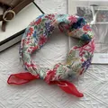 Gros plan sur un foulard en lin fleuri avec imprimés colorés et bordure rouge roulée - Tournesol Rouge