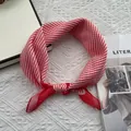Close-up of red and white striped cotton scarf tied in a knot on a white texture background - Red