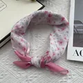Primer plano de un pañuelo de seda floral con flores de cerezo rosa y detalle de nudo - Patrón de flor de cerezo / Rosa