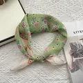 Dettaglio di un foulard in lino verde a fiori con bordi arrotolati su sfondo in maglia - 58x58cm / Verde