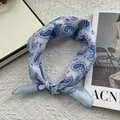 Detail van lichtblauwe paisley katoenen bandana in een knoop op witte textuur - 58*58cm / Blauw