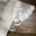 Gros plan d'un foulard en dentelle blanche avec des rubans sur un fond de lin vintage - Style de cour / Blanc