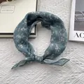 Detailaufnahme des hellblauen Seidenschals mit Blumenmuster auf feiner Spitze - Grün