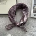 Detailed view of pink paisley print satin silk scarf tied neatly on a white fabric - Standard Square / Pink