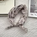 Detail eines Seidenschals mit Blumendruck und Rollsaum auf weißem Vintage-Stoff - Gebrochenes Weiß