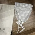 Gros plan d'un foulard en dentelle blanche avec broderie marguerite sur fond bois - Style Gypsophile / Blanc