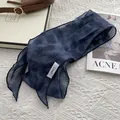 Detail of navy blue linen skinny scarf with fabric label on textured knit background - Dyed Dots