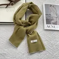 Close-up of grass green linen scarf with white contrast stitching on a textured background - 170x45cm / Yellow