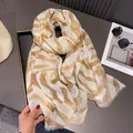 Detailed view of lightweight gradient shawl with artistic brown patterns and fringe edges - Khaki